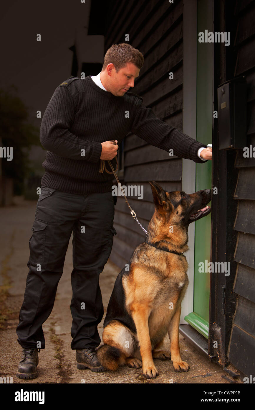 A security guard/dog handler checking security at a factory or trading