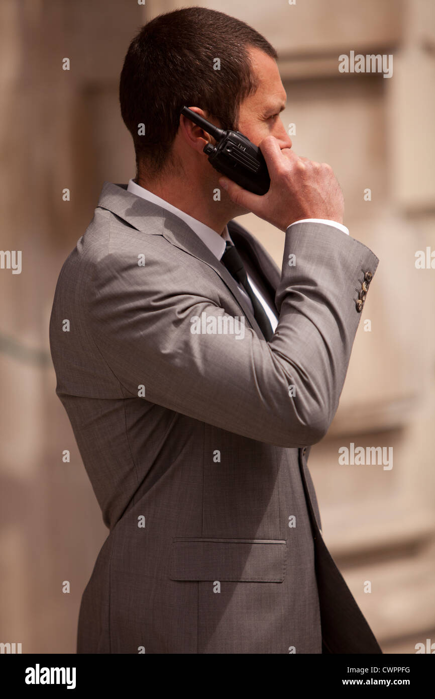 A close protection officer in radio contact with colleagues at a public event in front of a public building Stock Photo