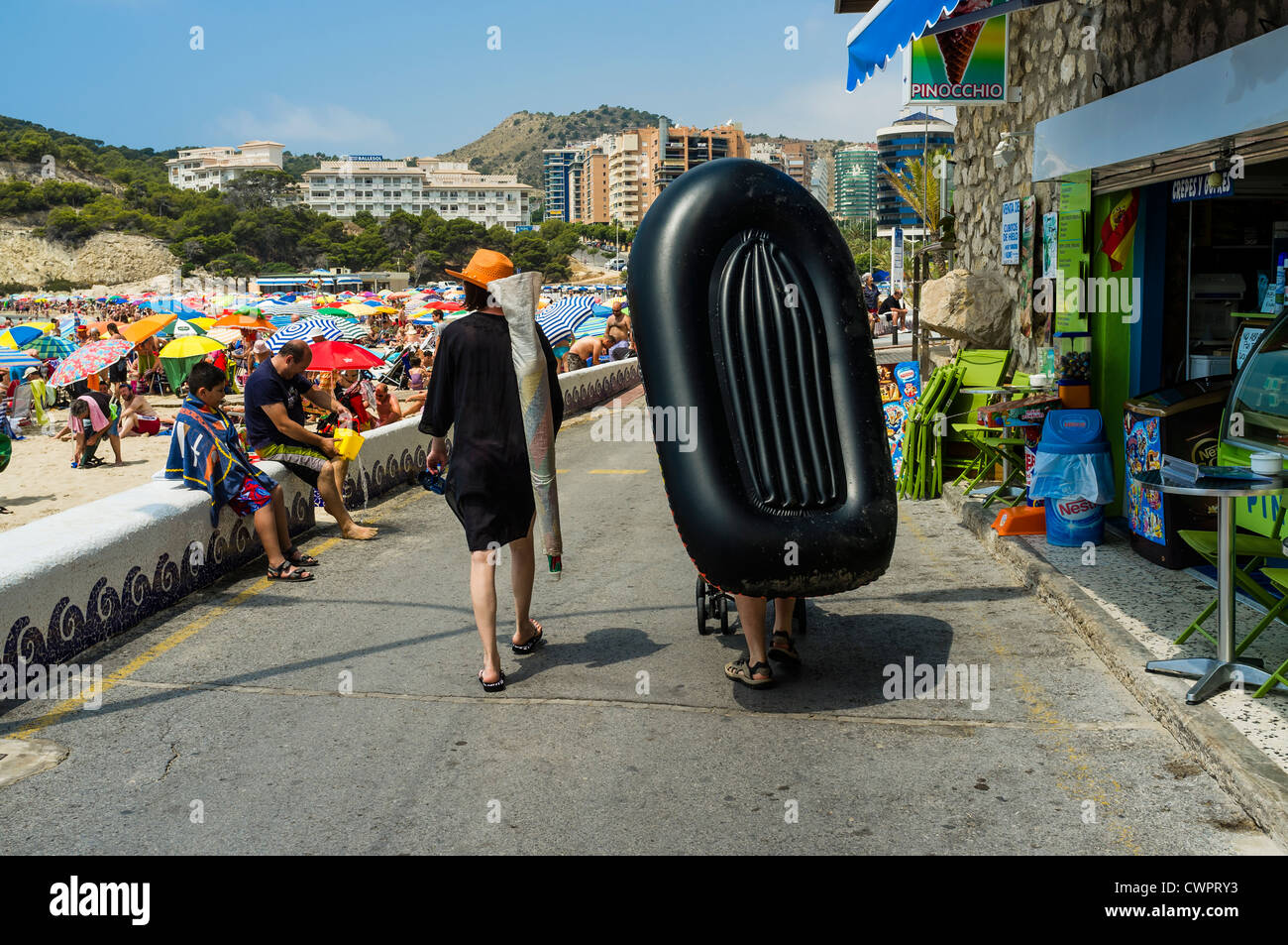 Tourist carrying a rubber inflatable dinghy in the seaside resort of