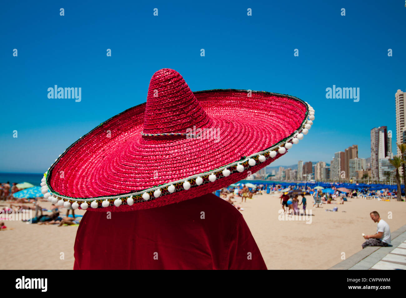 A man in ared straw sombrero on Benidorm Playa Levante. Stock Photo