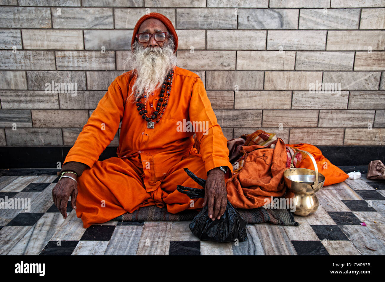 Sadhu wearing orange clothes and sitting in a temple. Jodhpur, Rajasthan, India Stock Photo