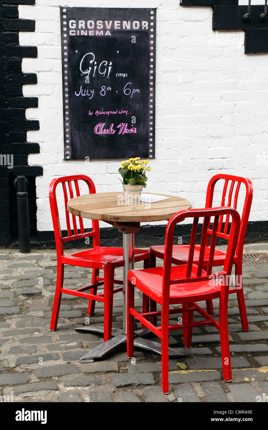 3 Red Chairs Around A Table With Flowers Outside The