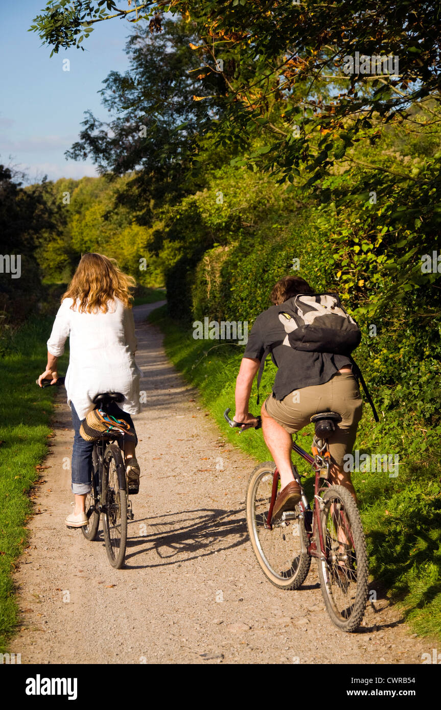Man and woman couple cycling on towpath by Kennet and Avon canal at Warleigh Stock Photo