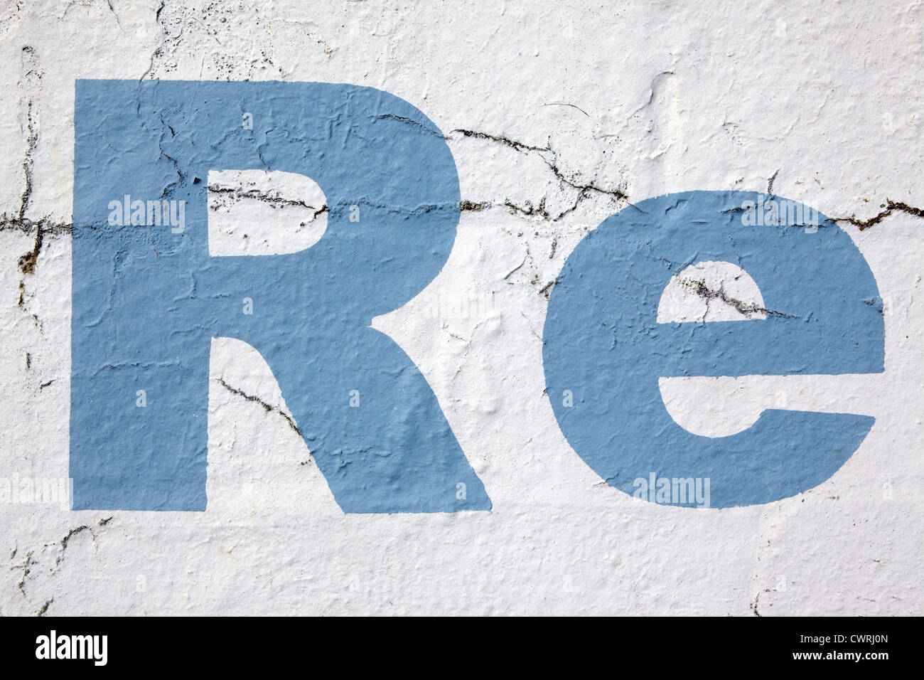 Lettering 'Re', stencil style sky blue paint on a white washed wall background, crumbling and distressed look, Cornwall, UK Stock Photo