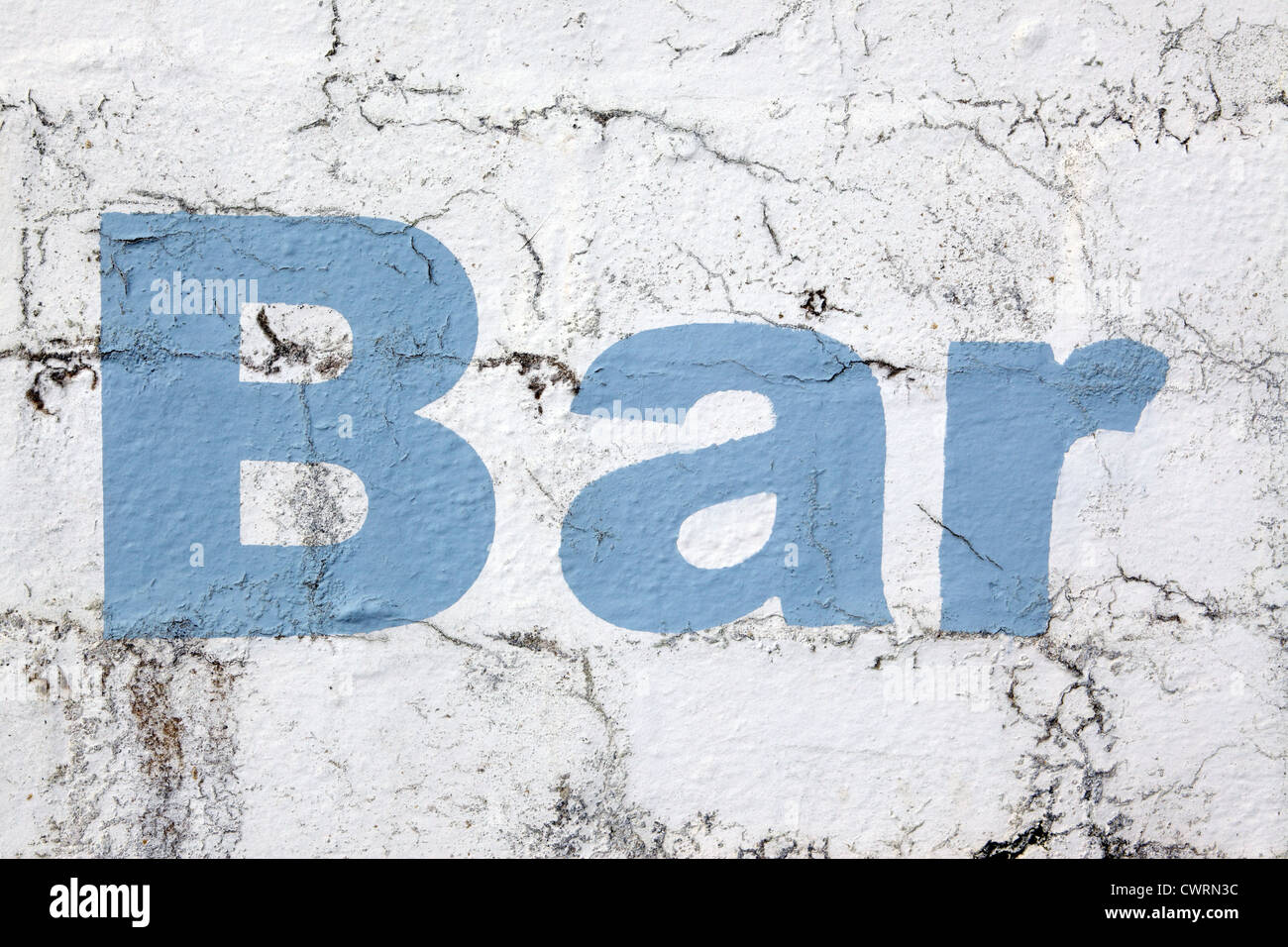 Lettering 'Bar', stencil style sky blue paint on a white washed wall background, crumbling and distressed look, Cornwall, UK Stock Photo