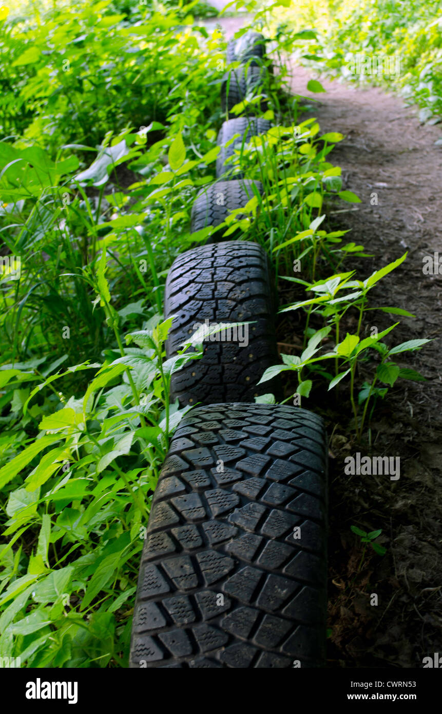 Forest path strengthen with old used car tires. Interesting decoration. Nature pollution. Stock Photo