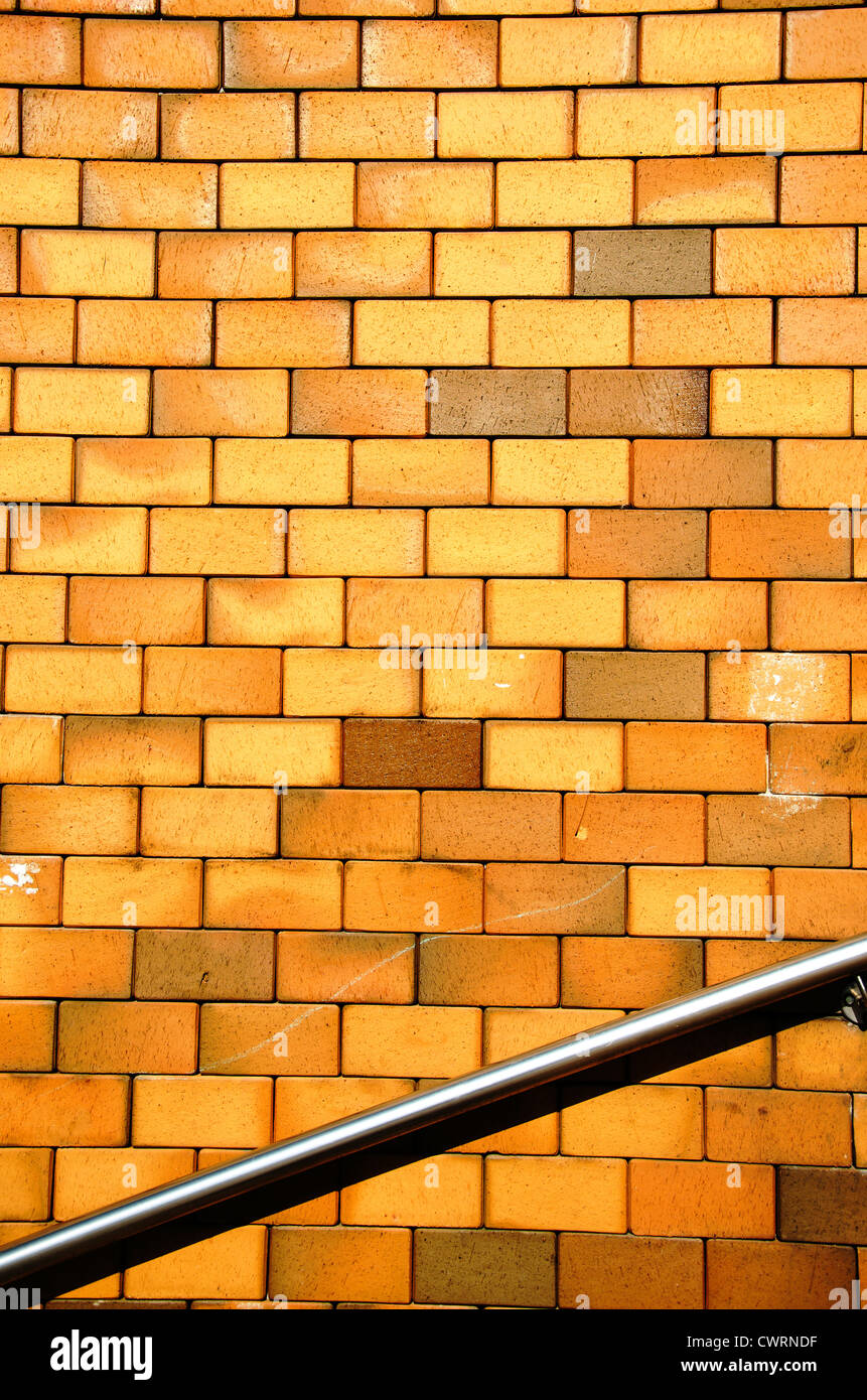 Background of yellow brick wall and steel stair railing. Stock Photo