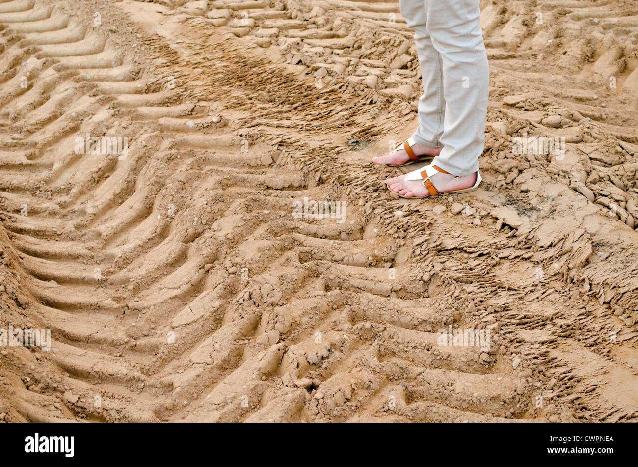 woman legs stand on quarry sand truck tracks. Stock Photo