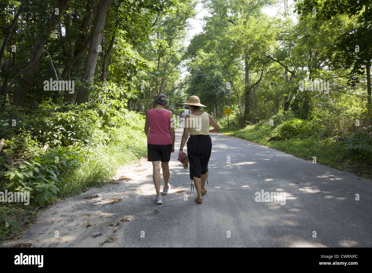 Female middle age friends walk down a country road near Riverhead, Long Island. Stock Photo