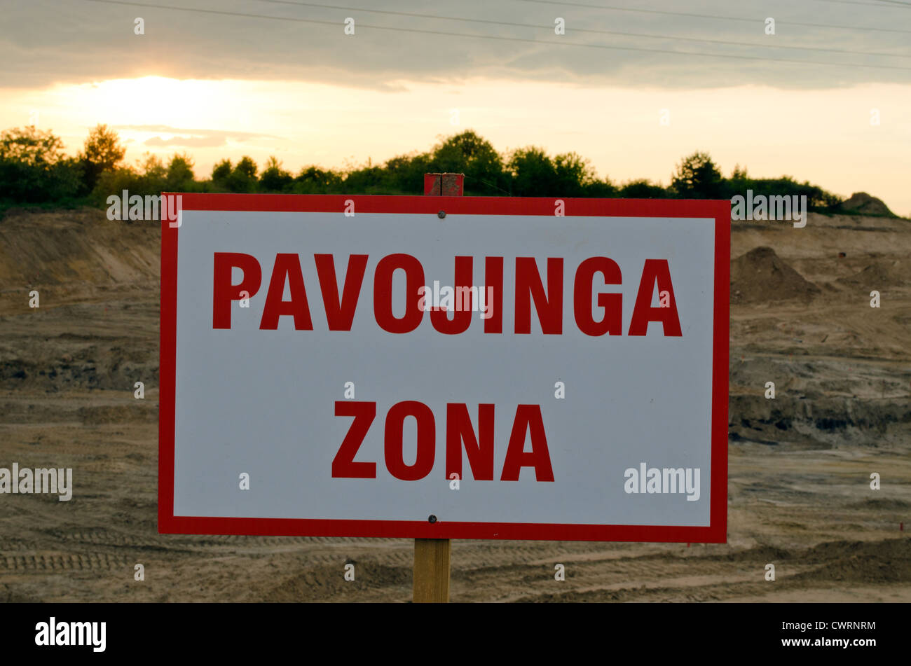 Lithuanian warning sign Danger Zone under construction site and sunset. Stock Photo