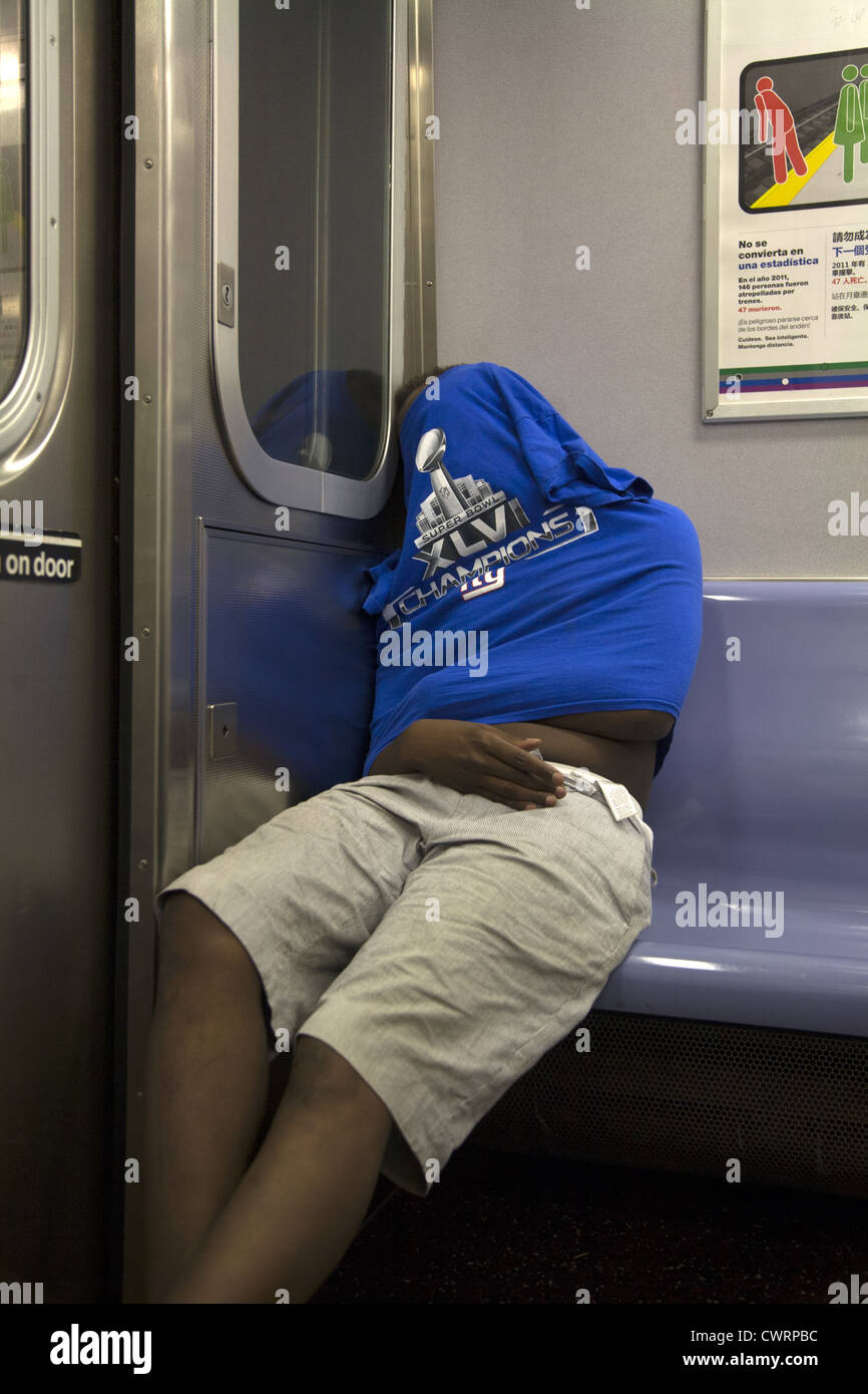 Young man sleeps somewhat anonymously while riding a subway train in Brooklyn, NY. Stock Photo