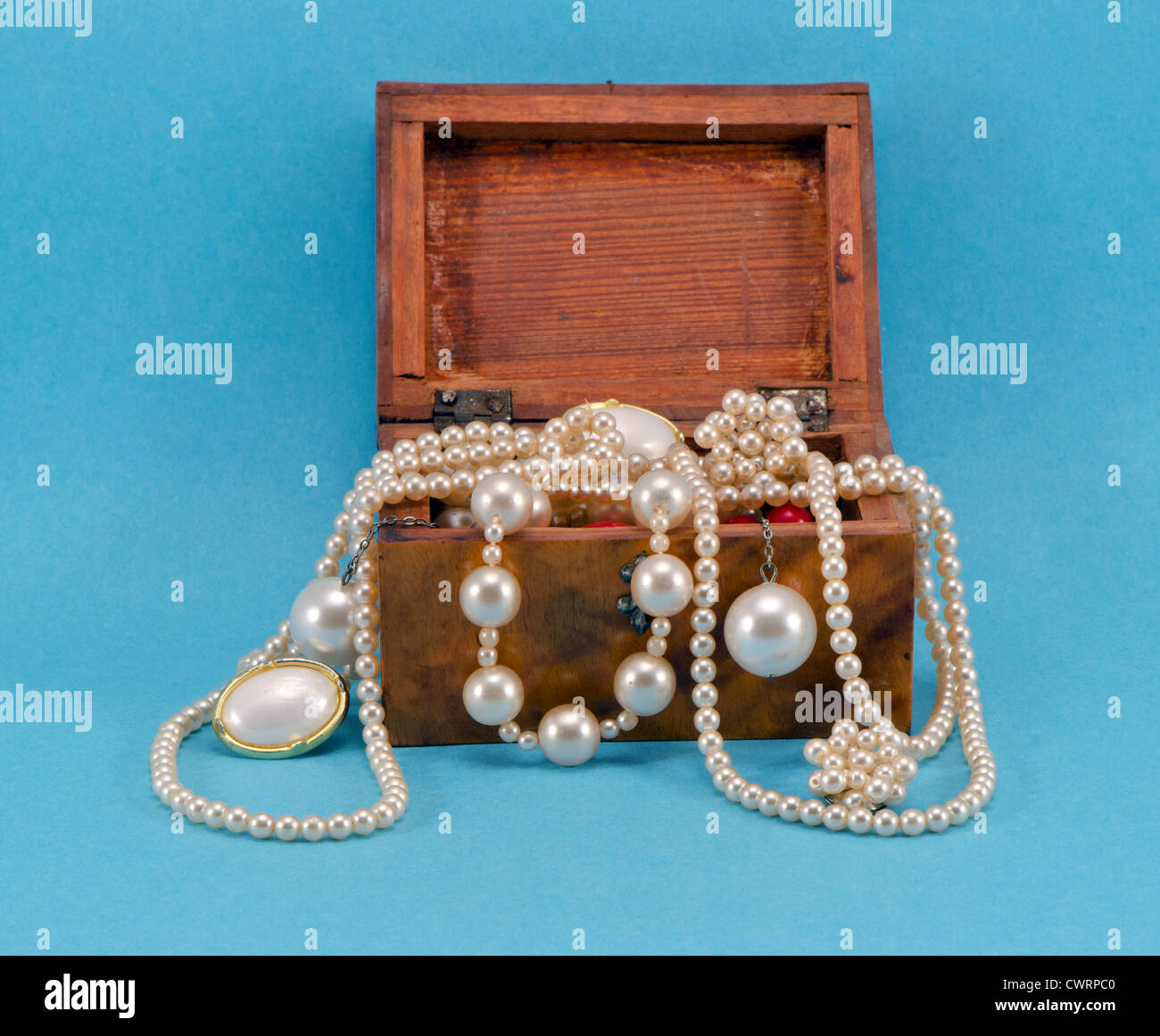 Pearl jewelry beads necklace earring in retro wooden box on blue background Stock Photo