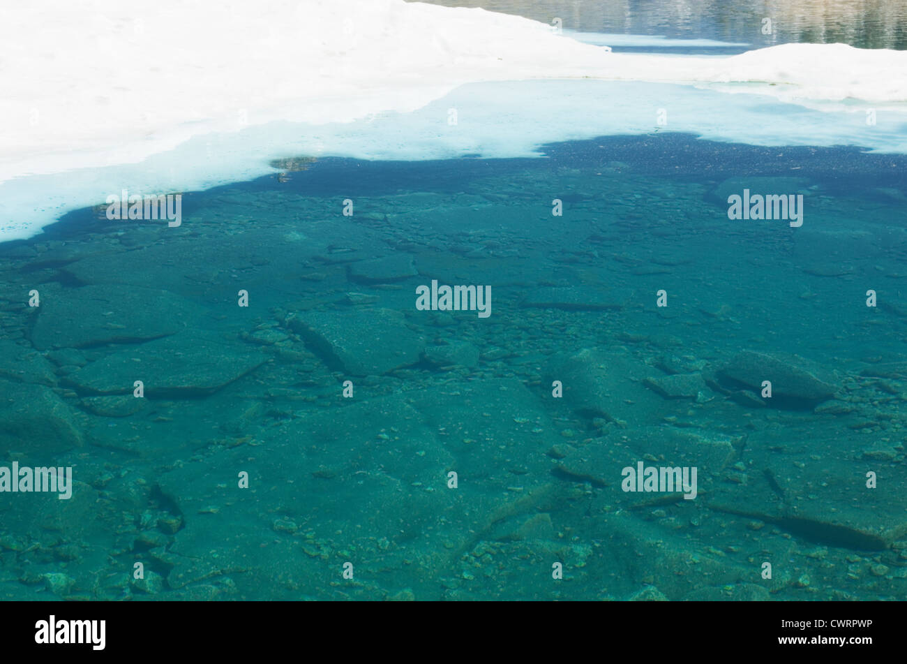 cold blue Sierra mountain lake with snow still floating in it Stock Photo