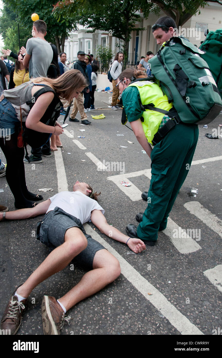 man lying on ground being approached by paramedics Stock Photo