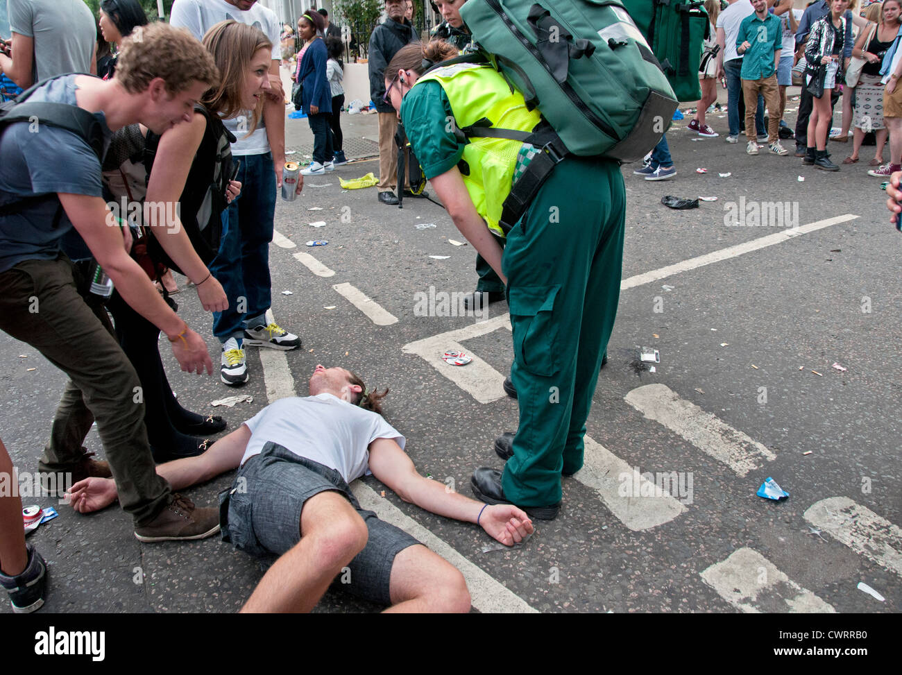 man lying on ground being approached by paramedics Stock Photo