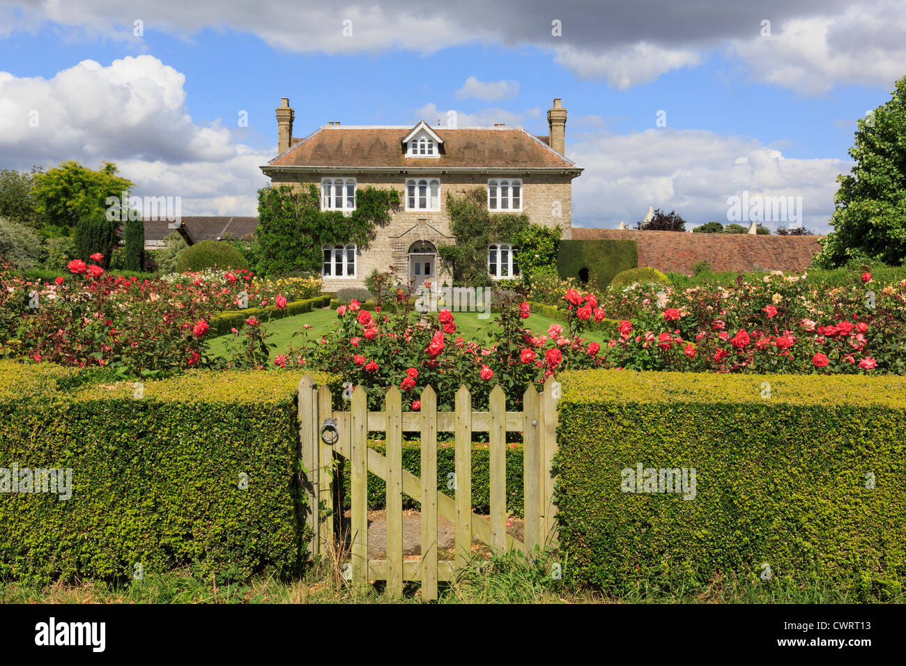 Hedge with gate to rose garden in front of a 19th century quintessential English country house in summer. Pluckley, Kent, England, UK, Britain Stock Photo