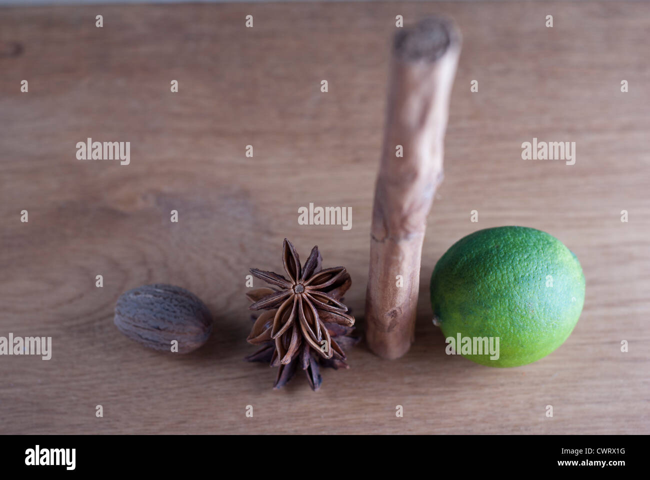 Still life, closeup of lime, cinnamon, star anise, and nutmeg on a wood surface. Stock Photo