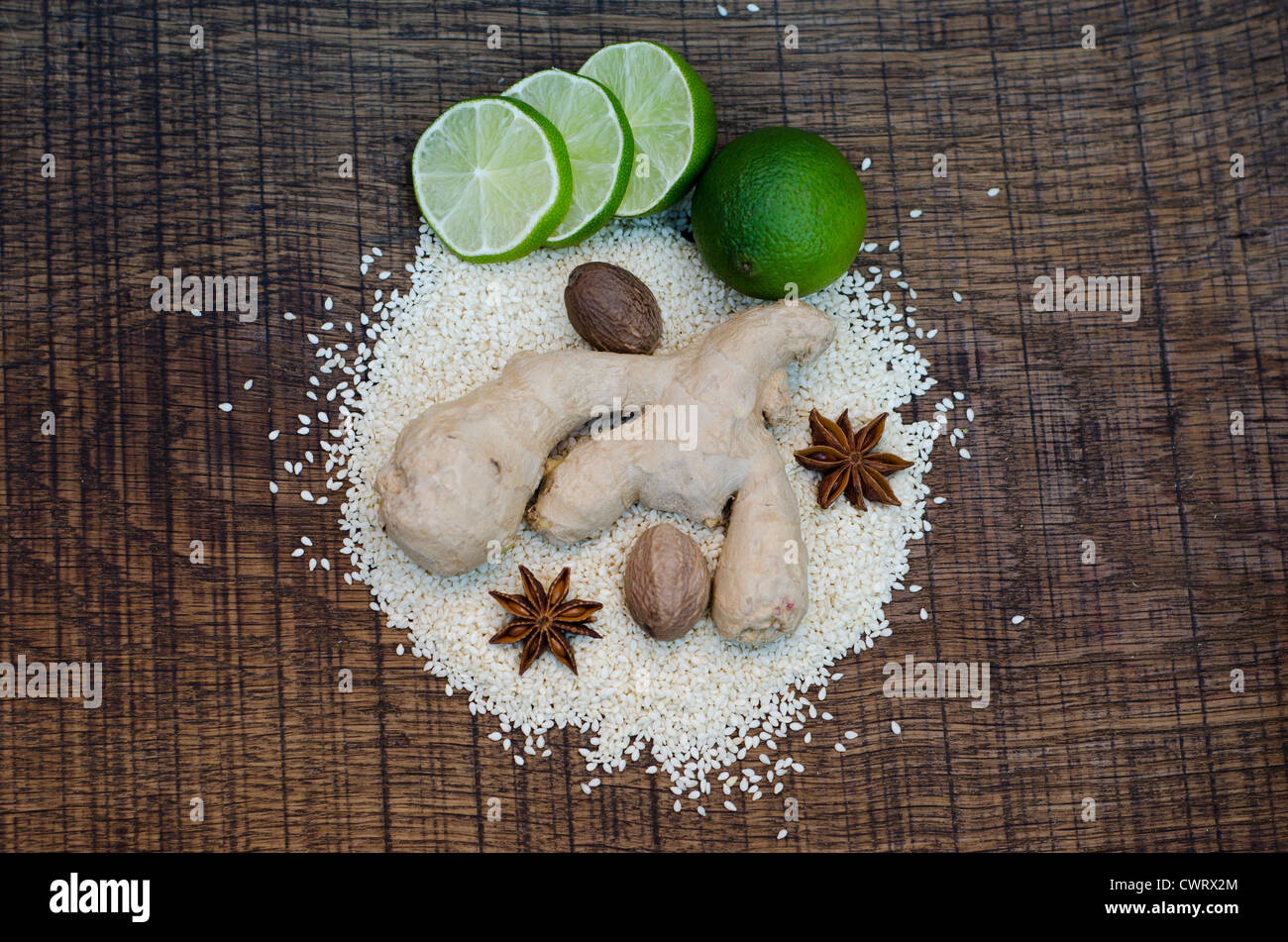 Looking down onto an arrangement of spices used in ayurveda healing and diet, on a dark oak wood surface. Stock Photo