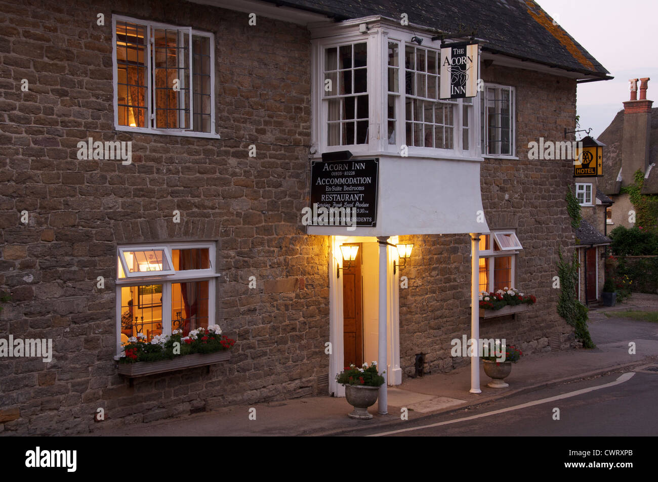 English pubs. The Acorn Inn, in the Dorset village of Evershot. A village pub, hotel and restaurant, its friendly lights glow in the evening. England. Stock Photo