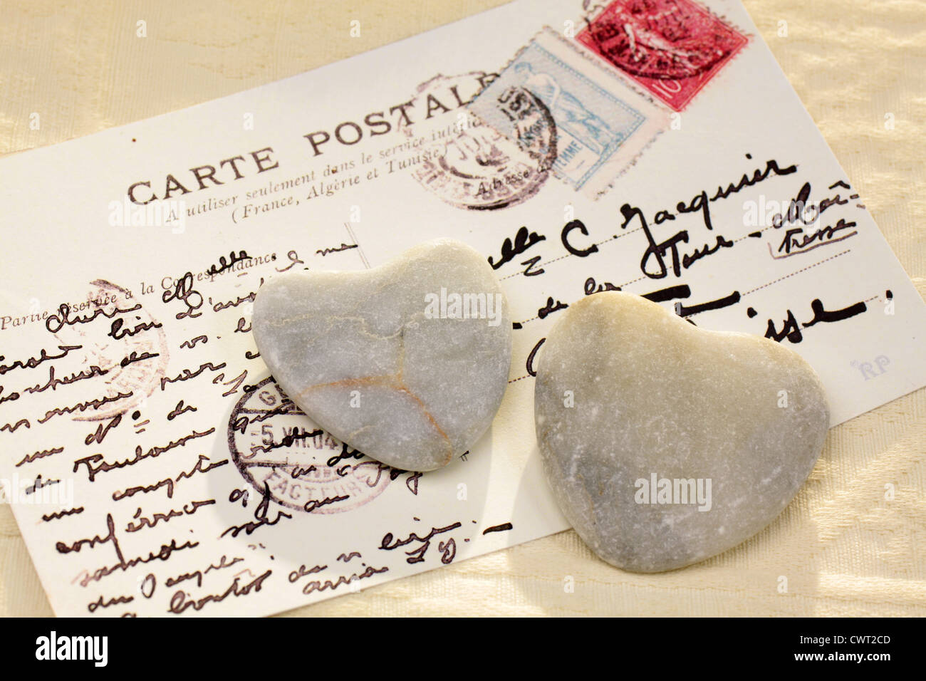 Two dark stone hearts with old French postcard Stock Photo