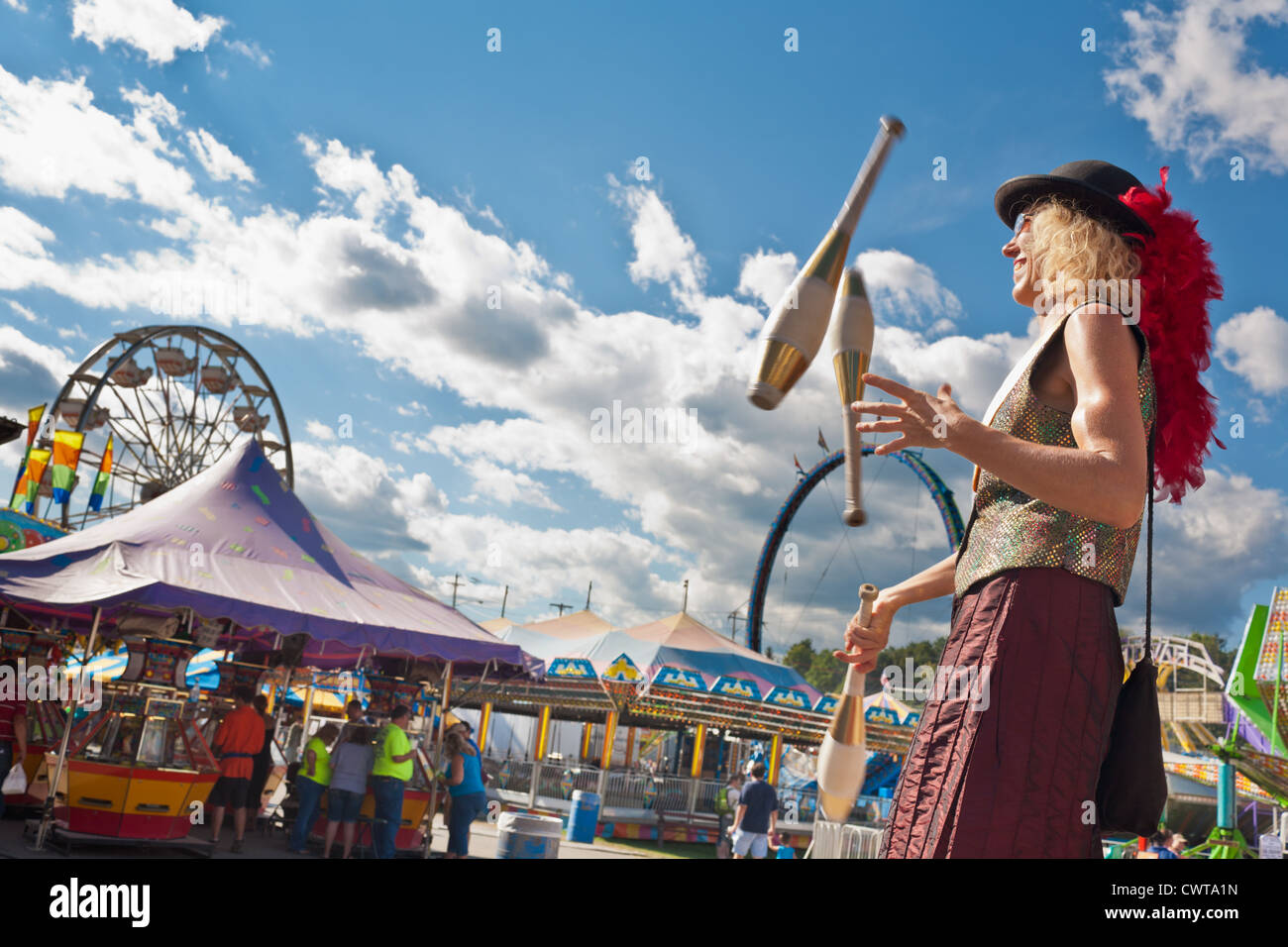Woman juggler on stilts in midway, Fonda Fair, Montgomery County, New York State Stock Photo
