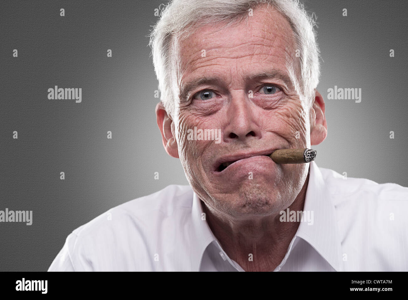 Studio shot of puzzled senior man with cigar in his mouth Stock Photo