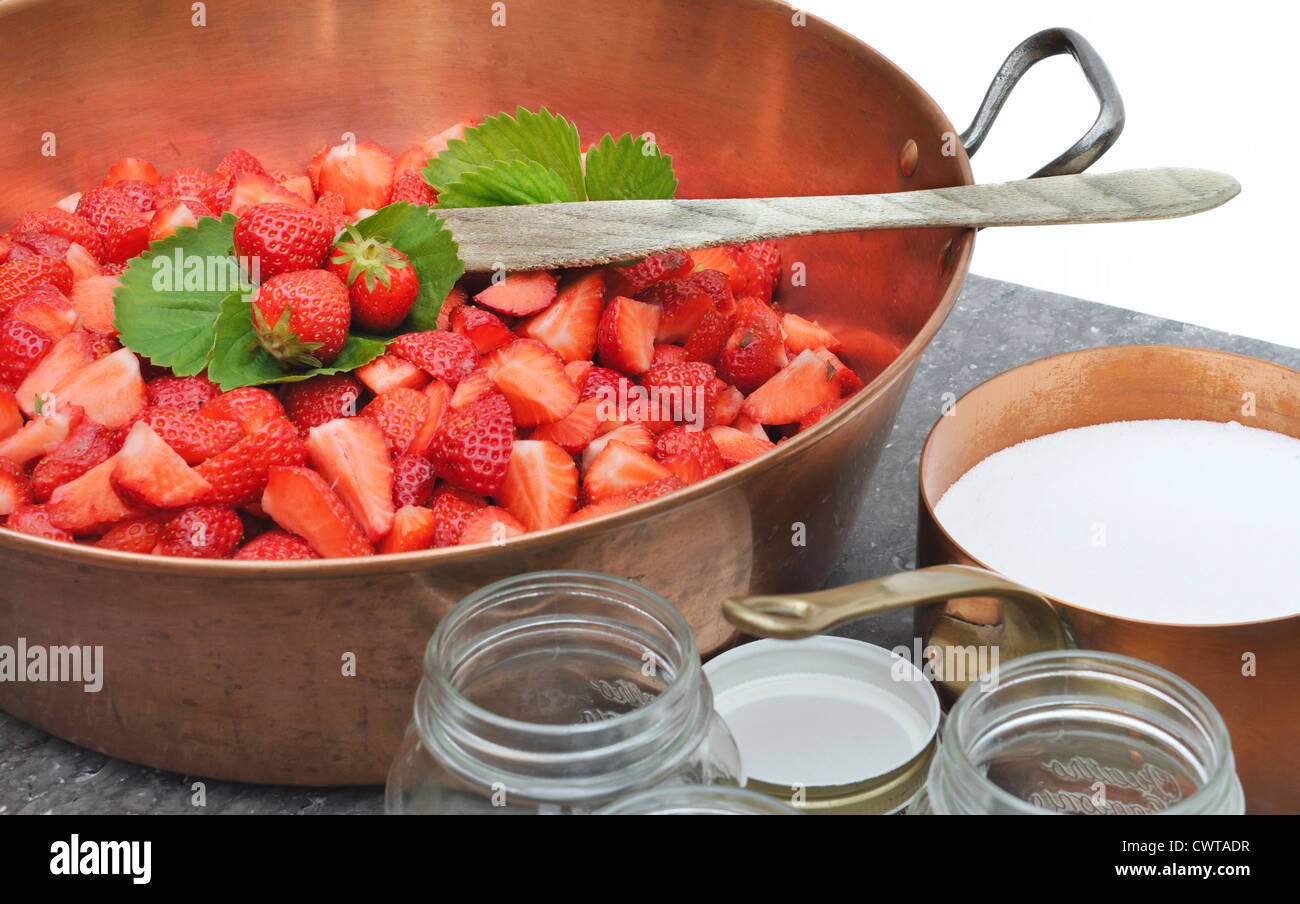Strawberries in a manufacturer with sugar and jars for making jam Stock Photo