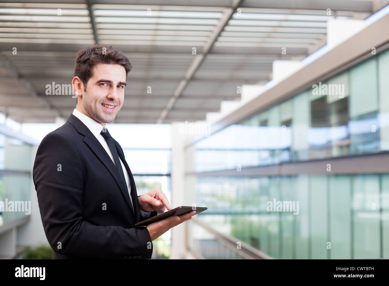 Smiling young businessman using his digital tablet at the office Stock ...
