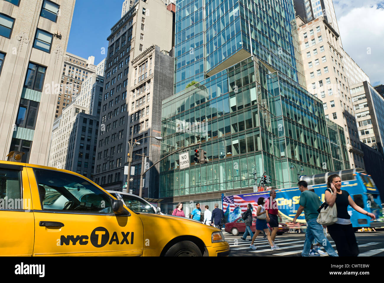 Traffic and yellow taxi cab and crowd of pedestrians at Fifth Avenue and 42nd Street in Midtown Manhattan, New York City. Stock Photo