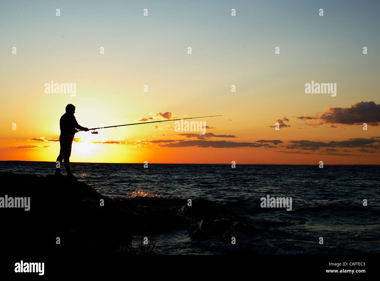 Silhouette of the fisherman at sunset Stock Photo - Alamy