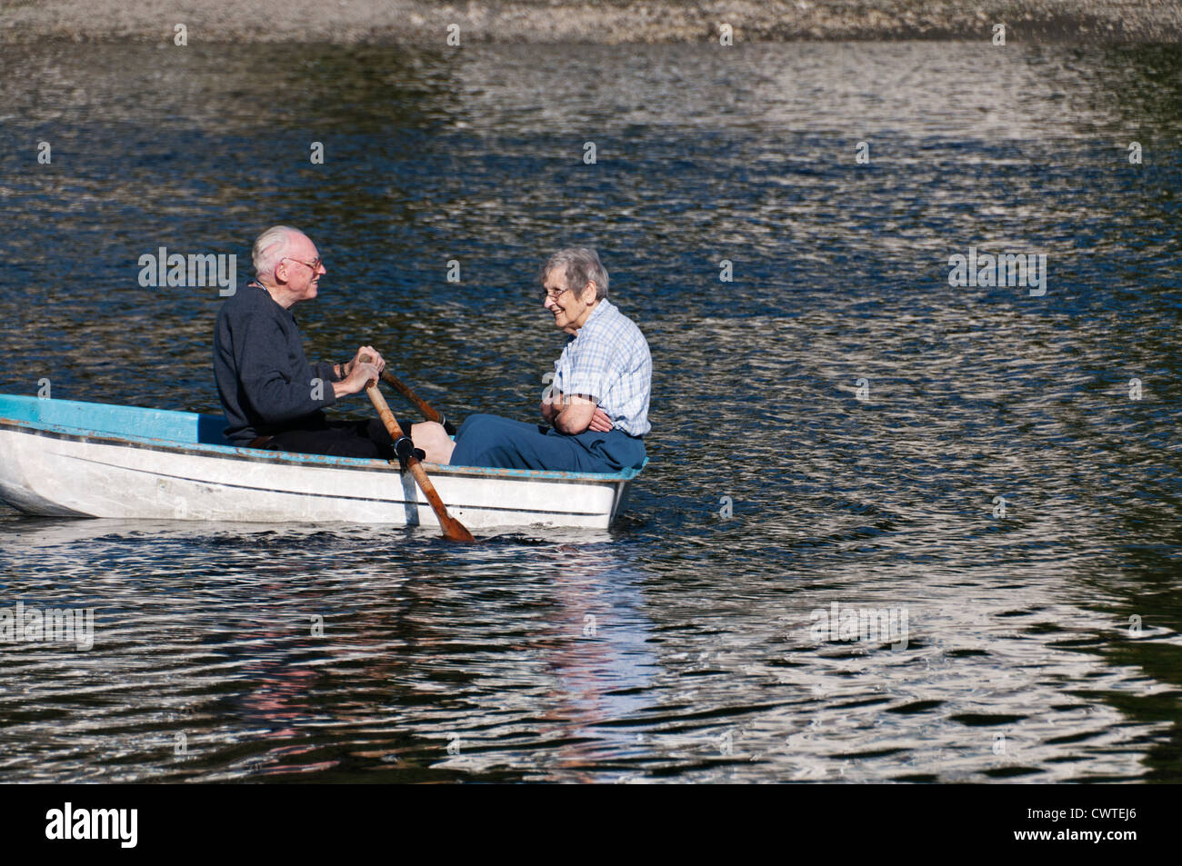An active, smiling, mature senior adult couple enjoys a summer day on Puget Sound in their rowboat. Stock Photo