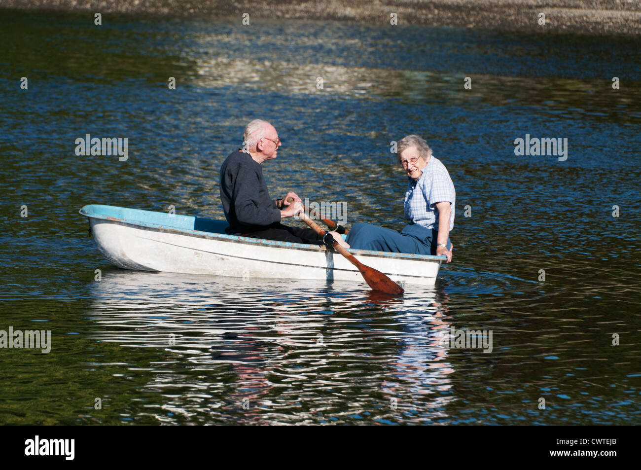 An active, smiling, mature senior adult couple enjoys a summer day on Puget Sound in their rowboat. Stock Photo
