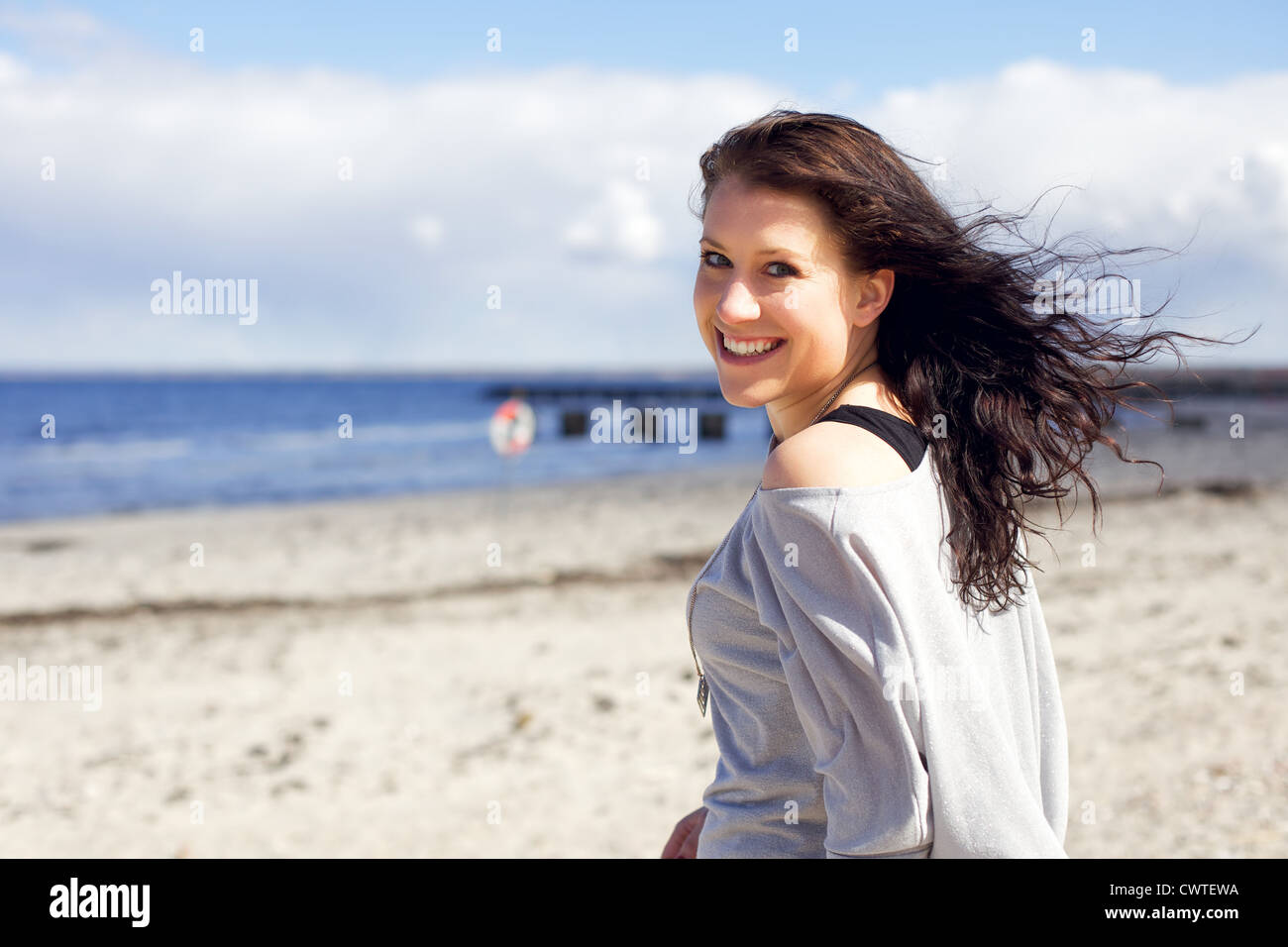A young adult woman enjoying a walk along the beach in the summer Stock Photo