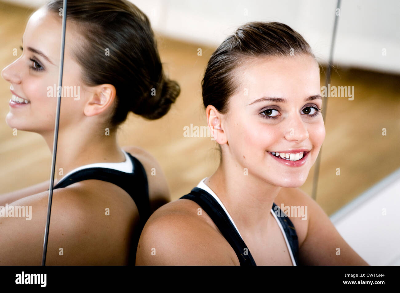 Sporty teenage girl leaning against mirror wall, portrait Stock Photo