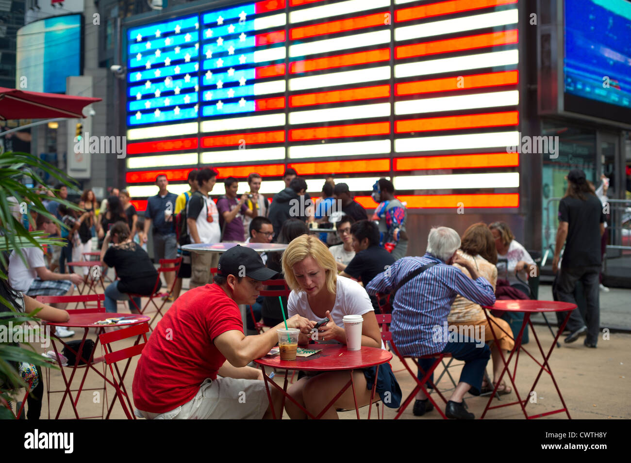 Tourists in front of an electronic American Flag which adorns the sides of the Armed Forces Recruitment booth in Times Square Stock Photo