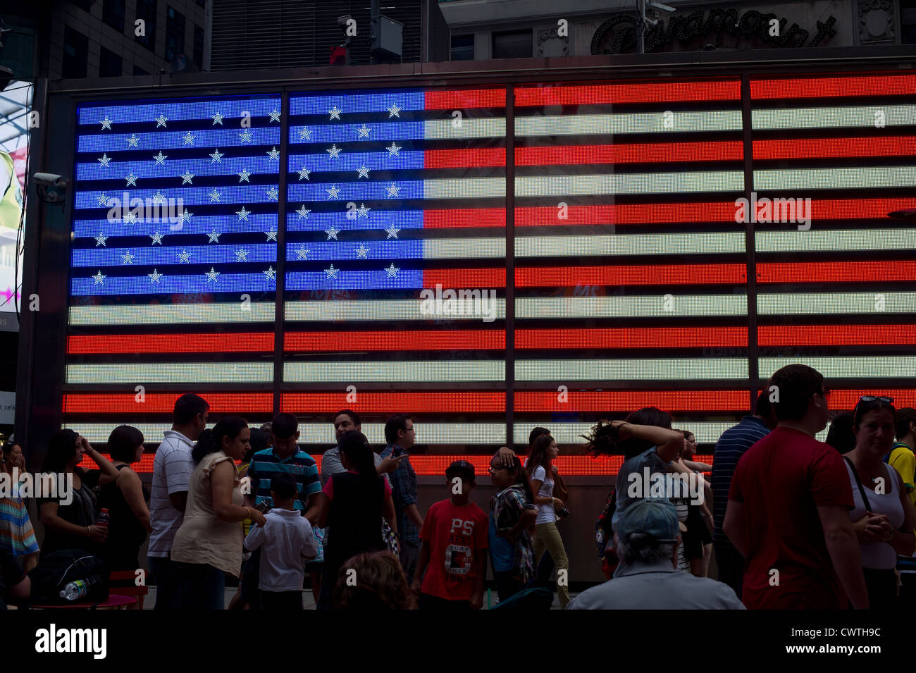 Tourists in front of an electronic American Flag which adorns the sides of the Armed Forces Recruitment booth in Times Square Stock Photo