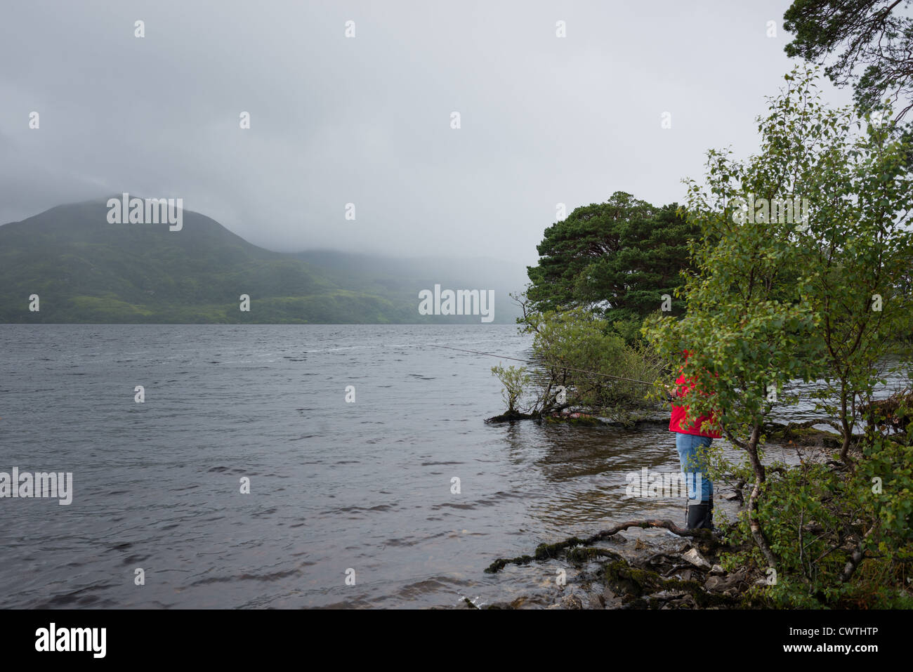 A man fishing in heavy rain on Lough Leane, Killarney National Park, County Kerry, Ireland. Stock Photo