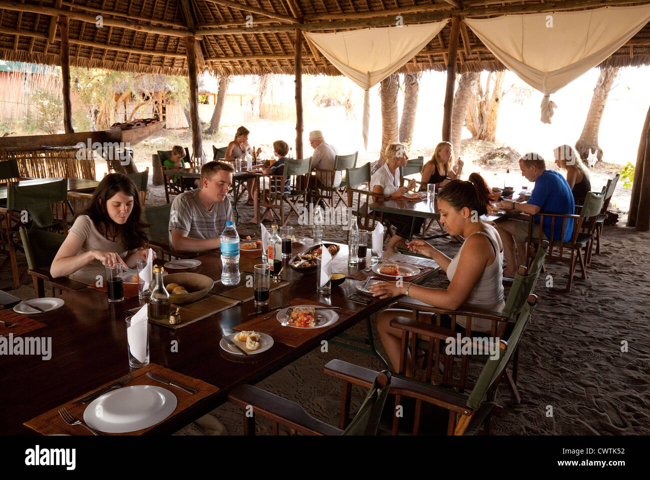 People eating in the restaurant area Lake Manze tented camp, the Selous Game Reserve Tanzania Africa Stock Photo