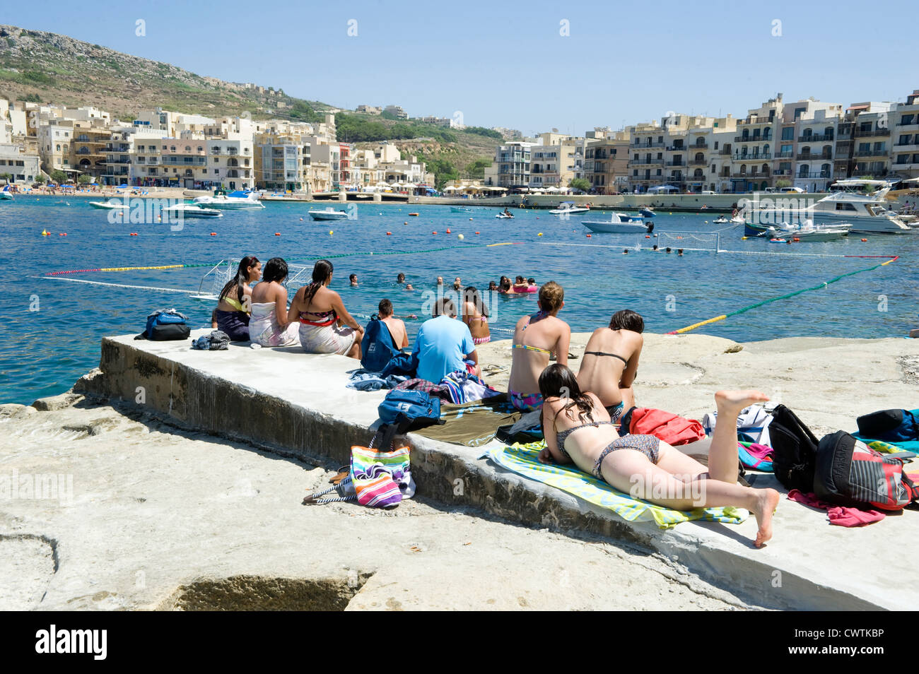 Teenagers watch watersport at Marsalforn on the Maltese island of Gozo Stock Photo