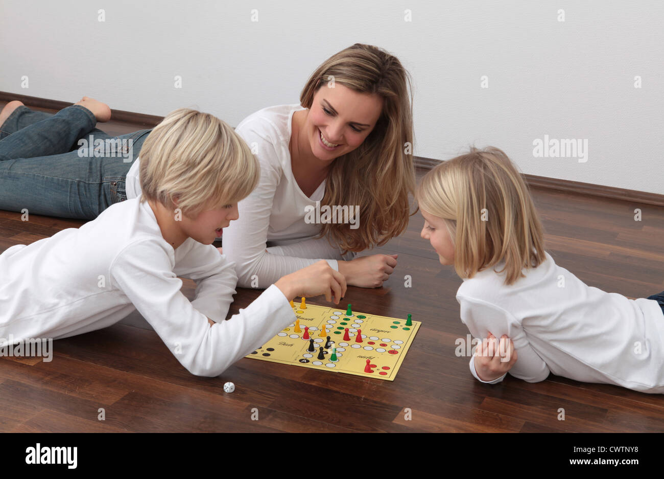 Mother and two children playing ludo on the floor Stock Photo