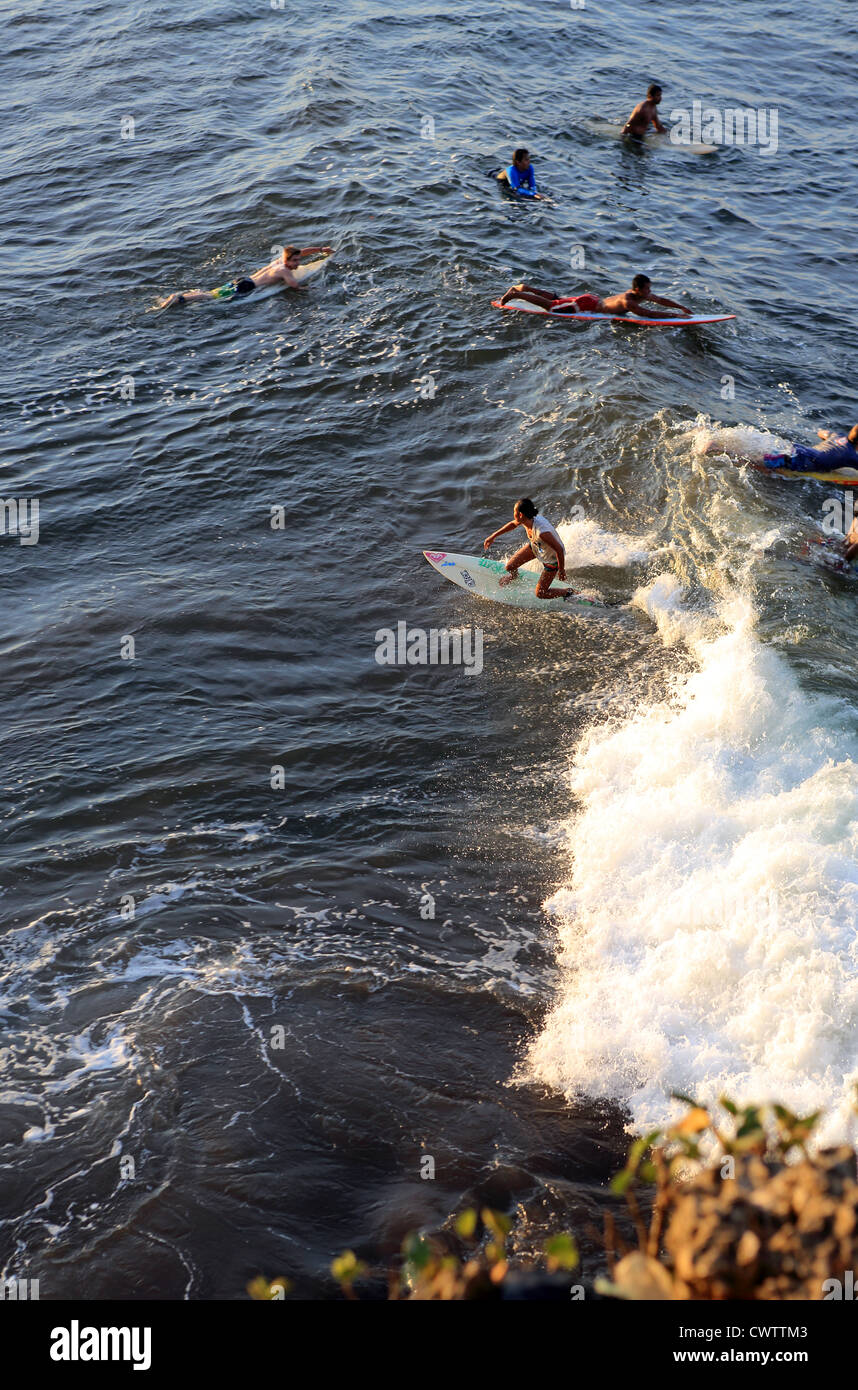 Female surfer surfing a wave at Batu Karas in West Java Stock Photo