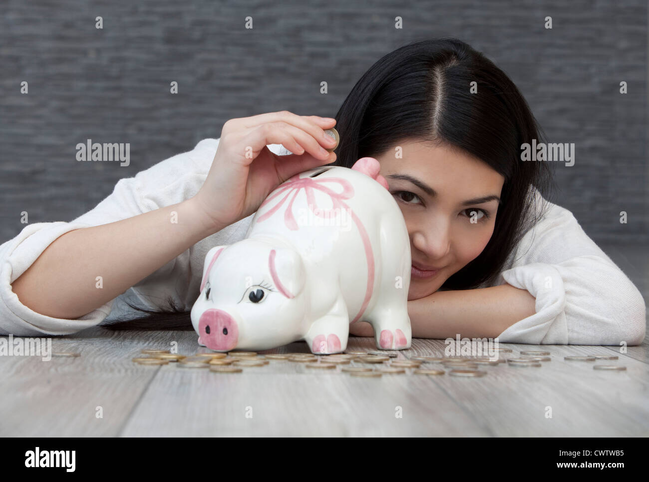 Young woman putting coin into piggy bank Stock Photo - Alamy