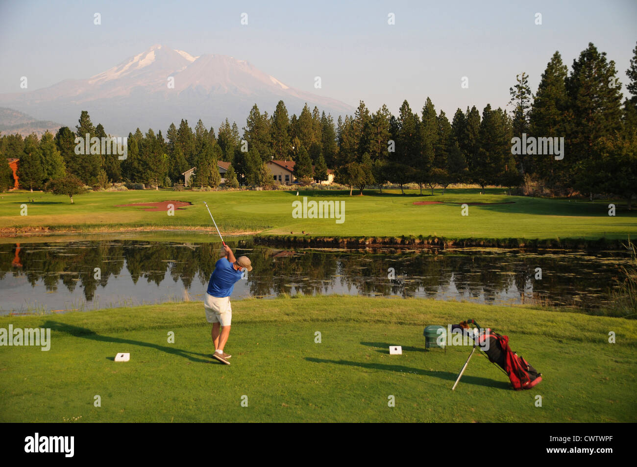 Man hitting across pond at Lake Shastina Golf Resort under the peak of Mount Shasta in Northern California Stock Photo