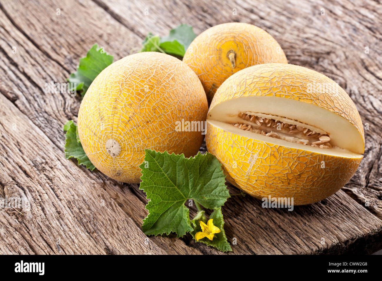 Melon with slices and leaves on a old wooden table. Stock Photo