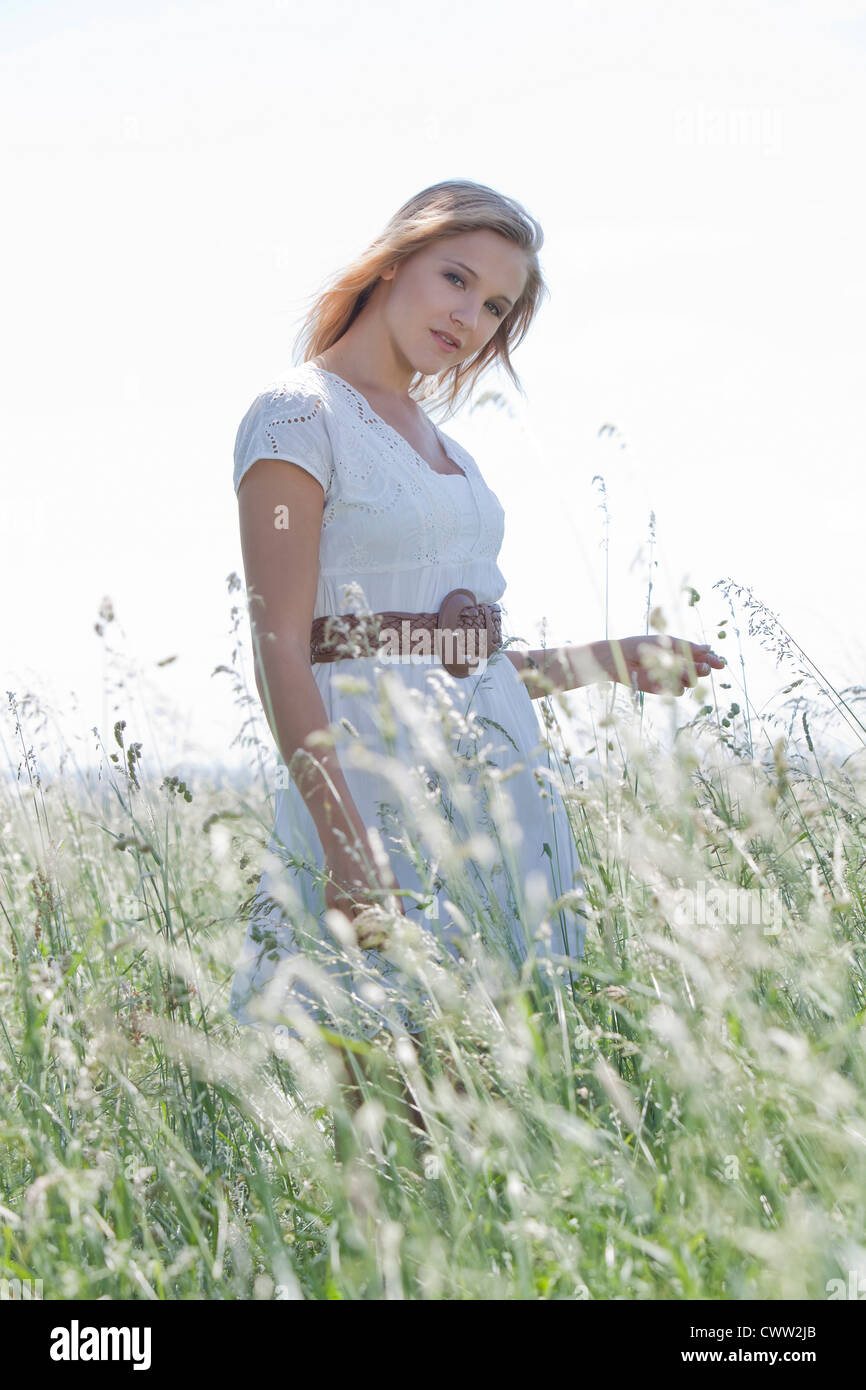 Attractive blond young woman standing in field Stock Photo - Alamy