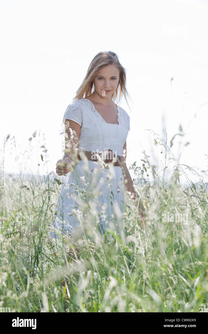 Attractive blond young woman standing in field Stock Photo - Alamy