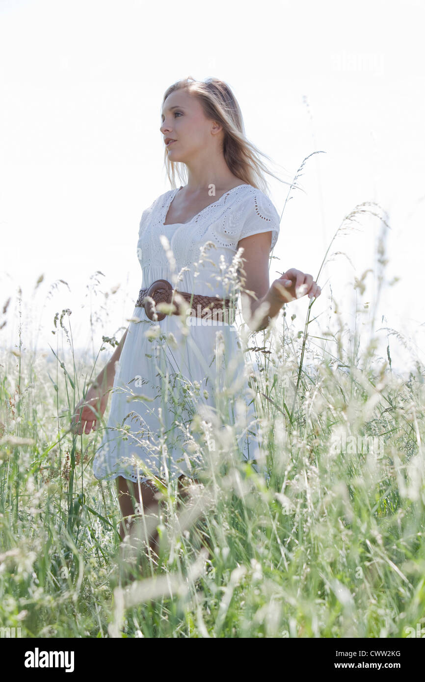 Attractive blond young woman standing in field Stock Photo - Alamy
