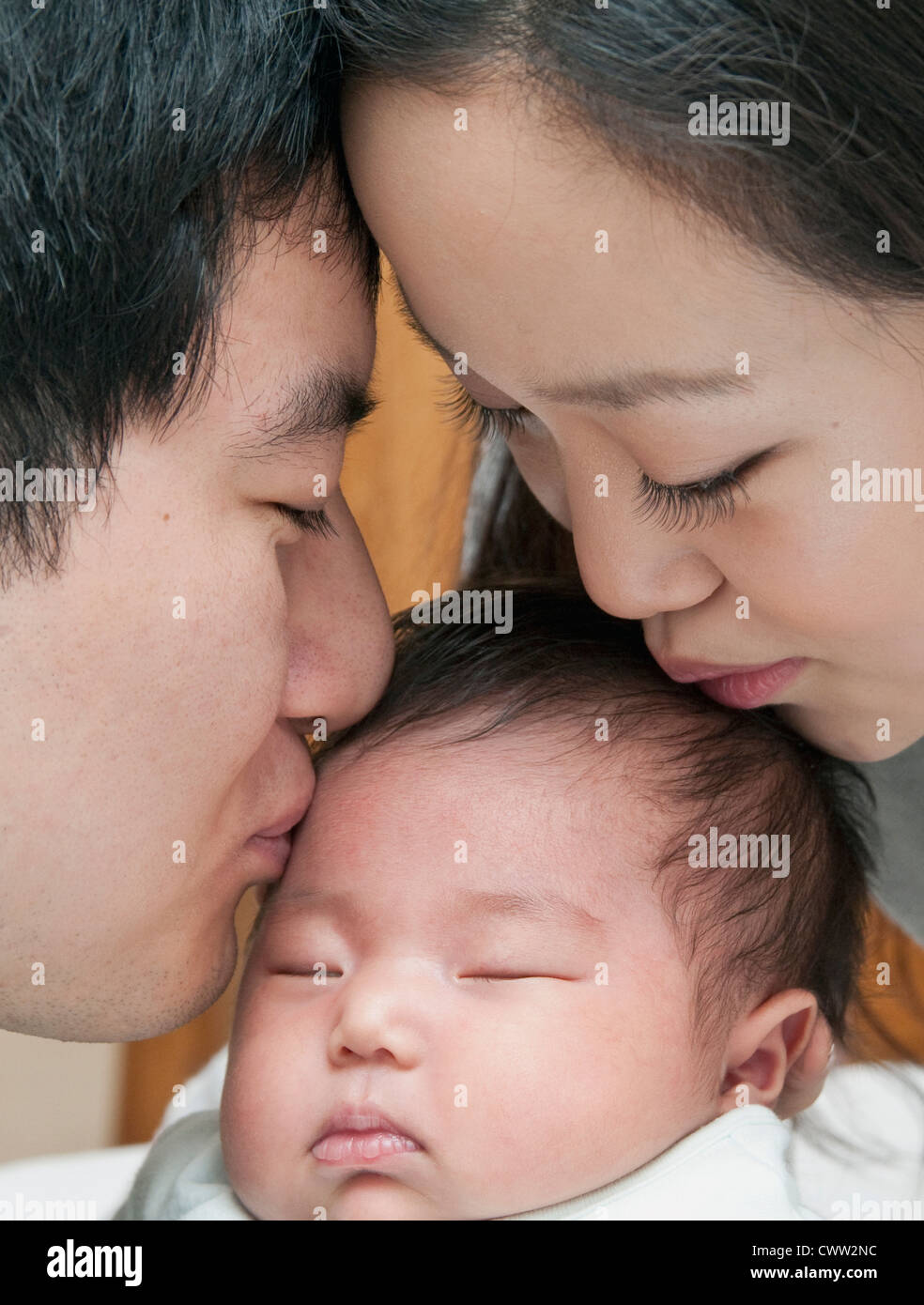 Parents kissing sleeping baby Stock Photo