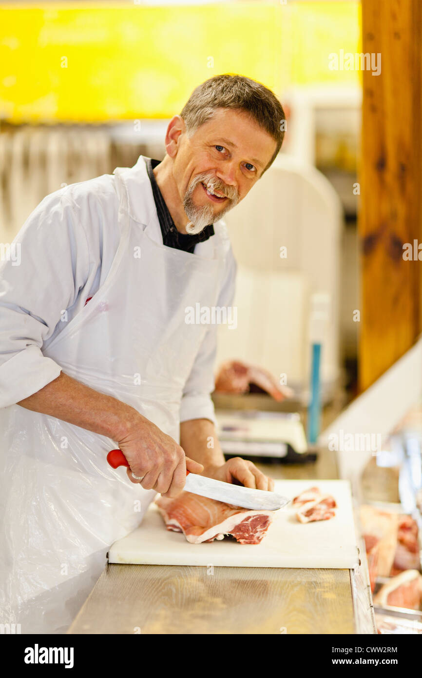 Butcher slicing meat at counter Stock Photo