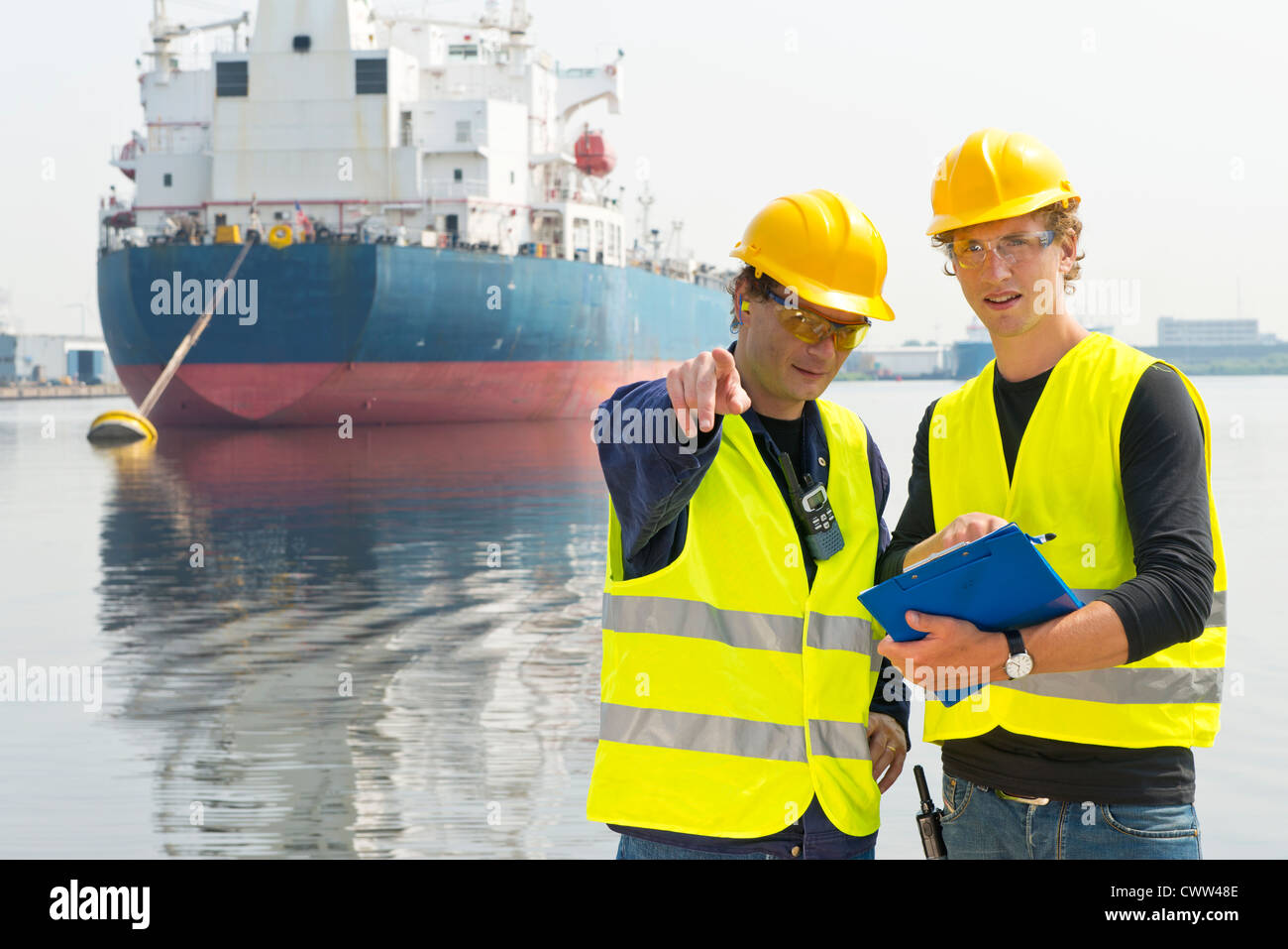 Two harbor engineers meeting, one pointing and explaining something to the other Stock Photo